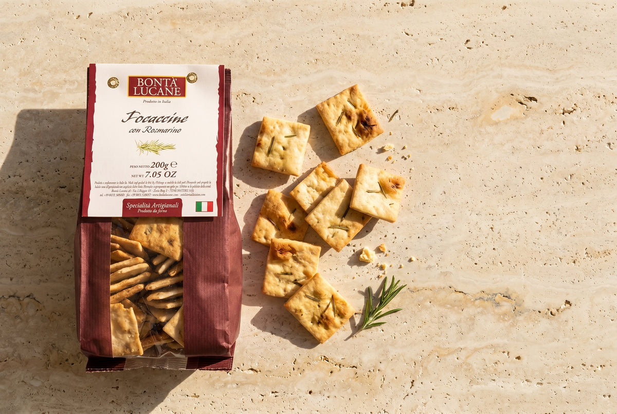 Bontà Lucane Focaccine al rosmarino auf Travertin-Tischplatte — lose Focaccine und Produkttüte